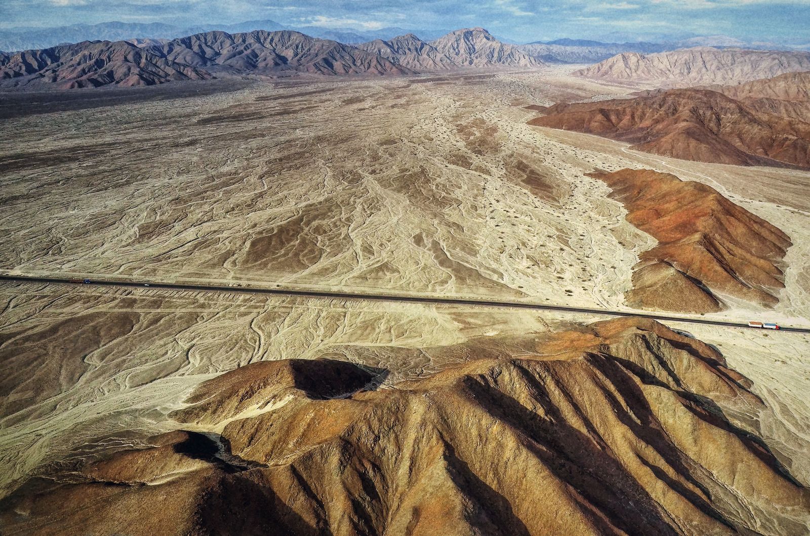 Vista aérea de la Panamericana Sur cruzando el desierto de Nazca, con un tráiler de carga en ruta